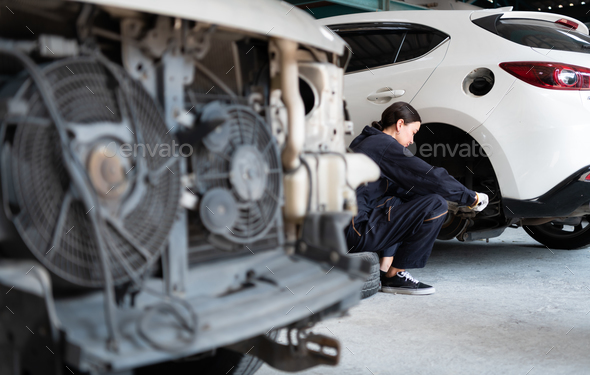 A female mechanic checking the condition of a car\'s brake discs and the condition of the tires