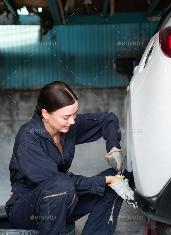A female mechanic checking the condition of a car\'s brake discs and the condition of the tires
