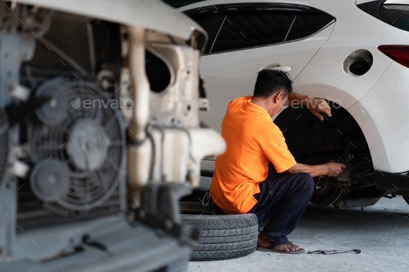 A auto mechanic checking the condition of a car\'s brake discs and the condition of the tires