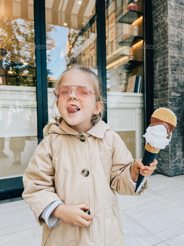 Little girl with her tongue hanging out posing with a big ice cream