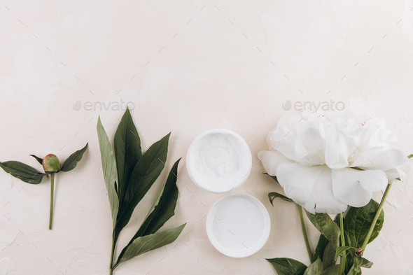 A cream mask on a light background with a delicate peony flower. Mock up image.