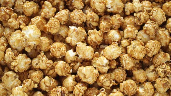 Close up of fresh sweet caramel popcorn rotates on board. Crispy snack for watching movie.