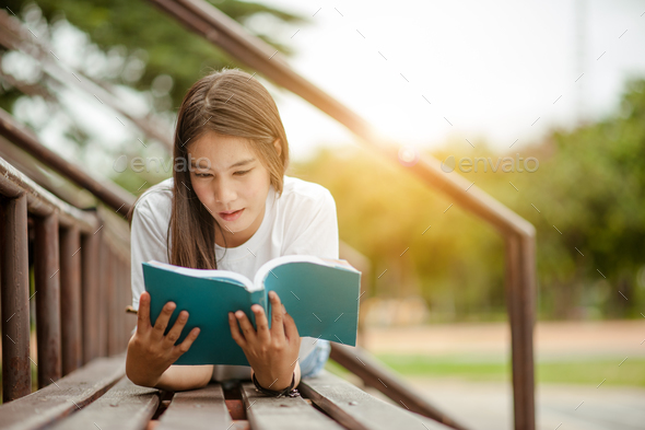 Beautiful young brunette woman lying on the amphitheater with a book in her hands. Romantic outdoor