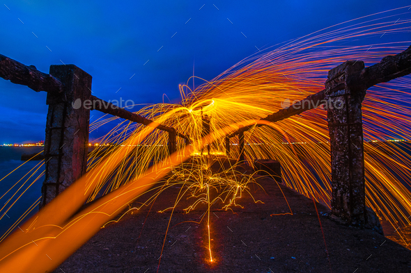 Showers of hot glowing sparks from spinning steel wool.Fire dancing show at twilight.Burning Steel W