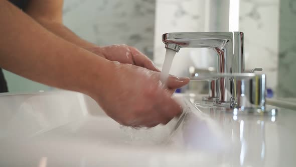 A Man Washes His Hands in the Bathroom Sink and Male Hands Closeup