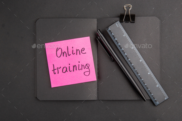 top view black notepad online training written on sticky note ruler pen binder clip on dark