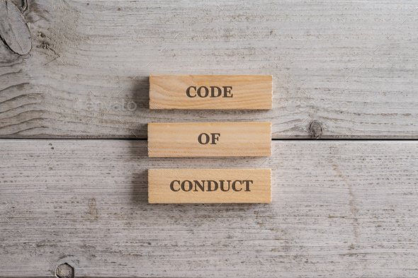 Code of conduct sign spelled on a stack of three wooden blocks