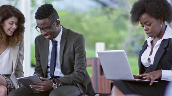 Colleagues Working on Tablet and Laptop Outdoors alt
