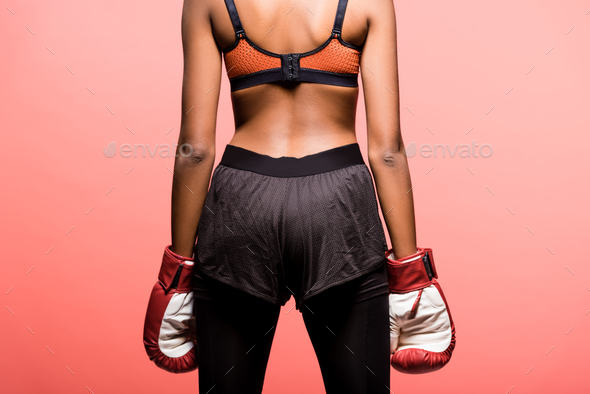back view of african american sportswoman in boxing gloves isolated on coral