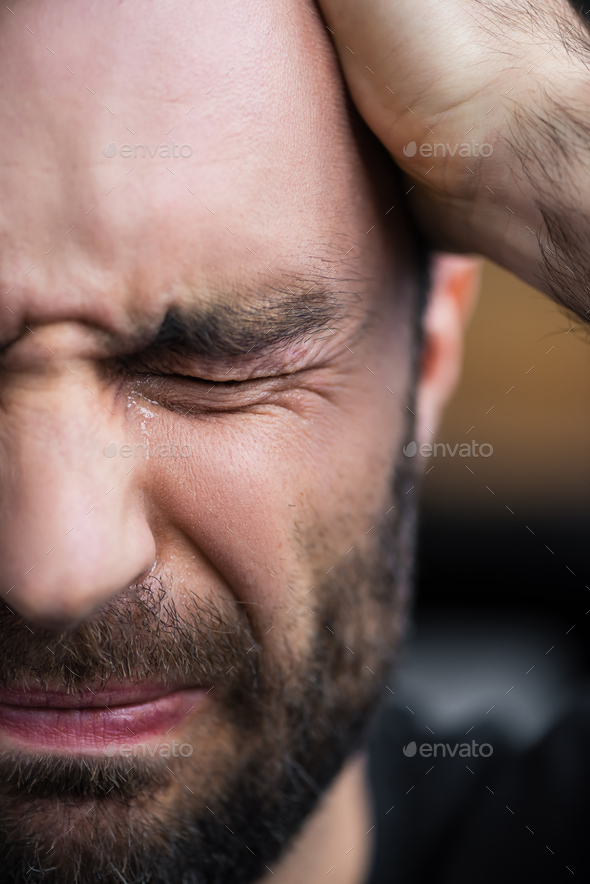 partial view of depressed bearded man crying with closed eyes