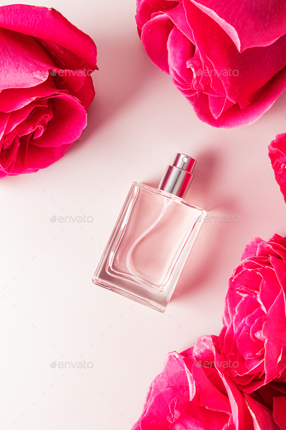 Top vertical view of a beautiful bottle of cosmetic spray among the heads of a garden rose.