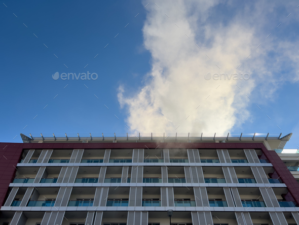 Smoke from a fire over the roof of a high-rise building against the blue sky