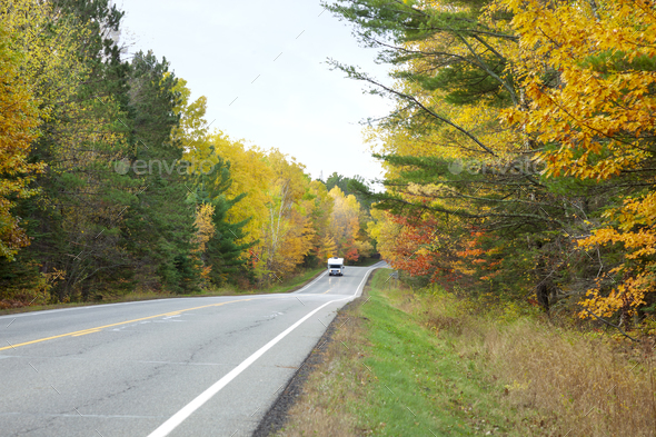 Camper drives along a Minnesota highway lined with trees in autumn color - Stock Photo - Images