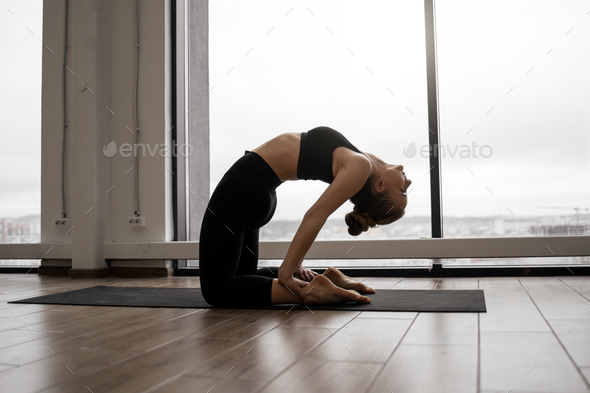 Woman doing Camel position Stock Photo by ©microgen 115159034
