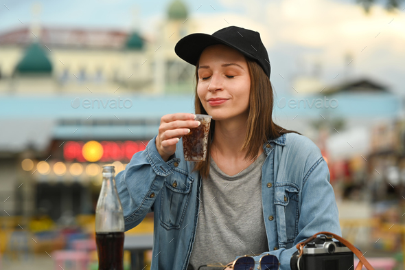 Young hipster woman in jean jacket drinking cola