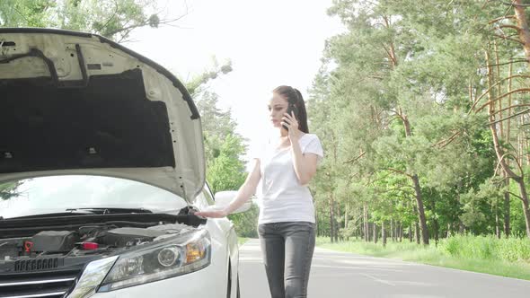 Beauitful Woman Looking Under the Hood of Her Broken Car on Countryside Road alt