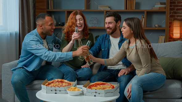 Happy multiracial friends celebrate festive event clink beer bottles eat pizza order food delivery