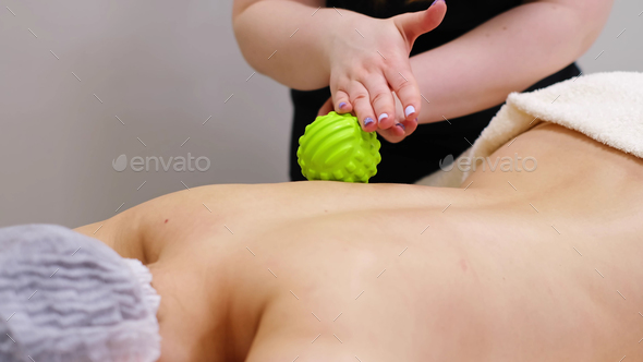 Woman at the physiotherapy receiving ball massage from therapist.