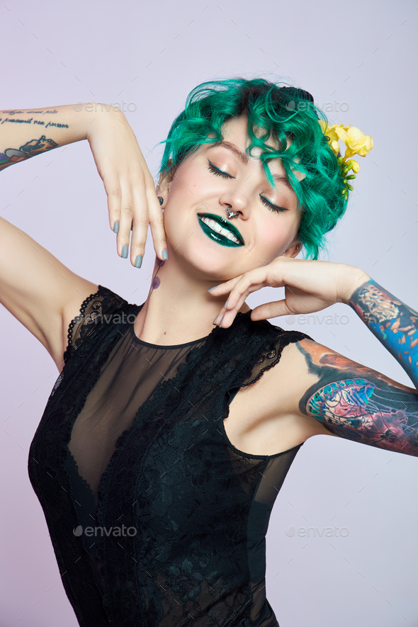 Woman with creative green coloring hair and makeup, toxic strands of hair. Bright color curly hair
