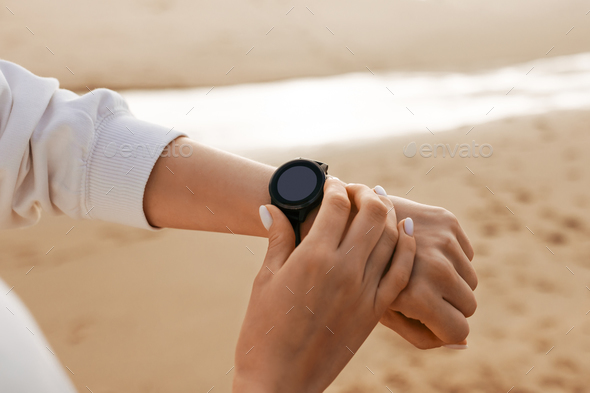 Time to start. Sporty young woman using smartwatch, checking fitness tracker, modern gadget with