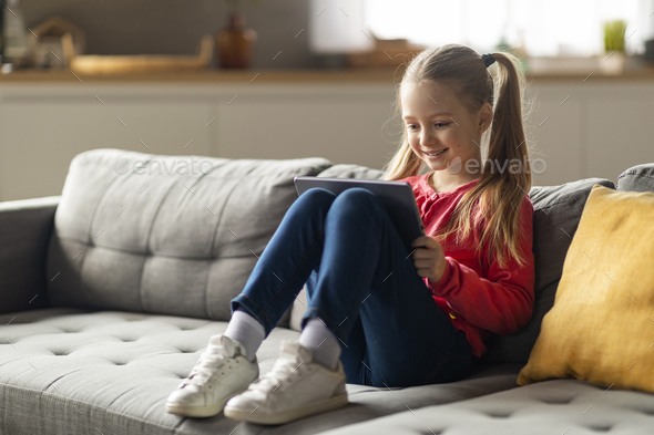 Cute little girl holding and using digital tablet smiling showing