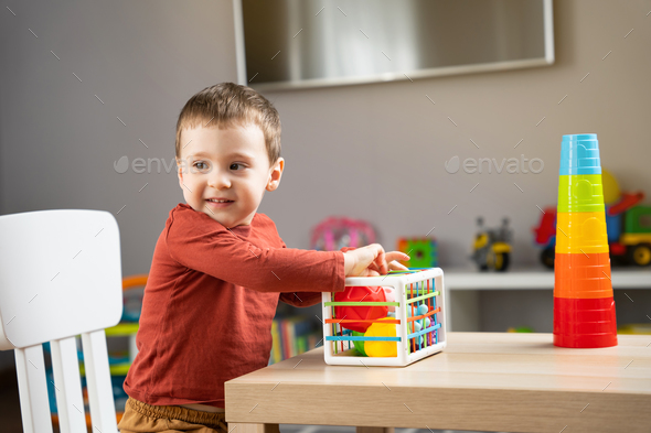 A cute little toddler boy of two years old plays with multi-colored balls - Stock Photo - Images