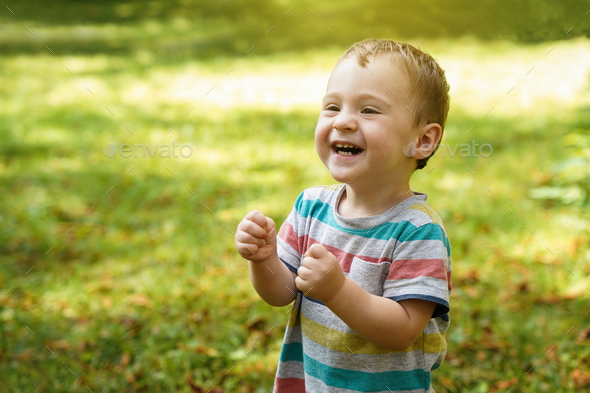 Happy toddler boy playing in the park on a sunny day. - Stock Photo - Images