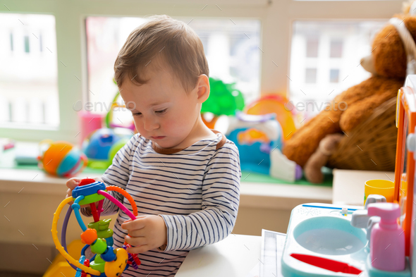 Toddler boy plays with educational toys in the children's room.  - Stock Photo - Images