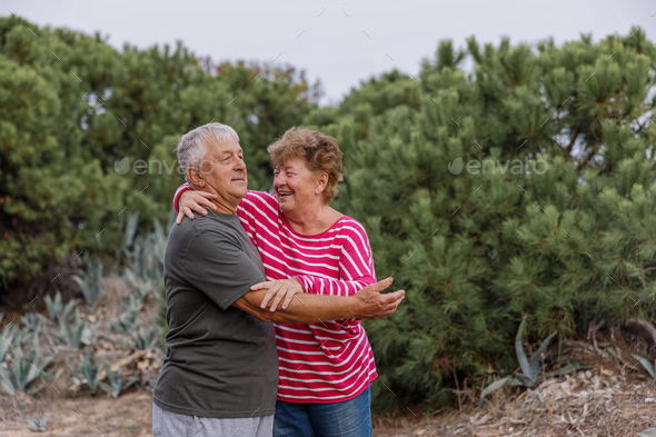 Happy elderly couple embracing in park on sunny day, love together in Valentines day concept