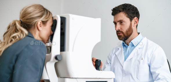 Male ophthalmologist checks a patient\'s vision at an opticians shop or ophthalmology clinic