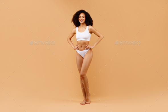 Cheerful Attractive Black Lady Posing in Underwear on Beige Stock