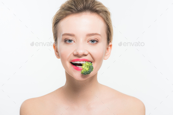 attractive naked woman eating green ripe broccoli isolated on white