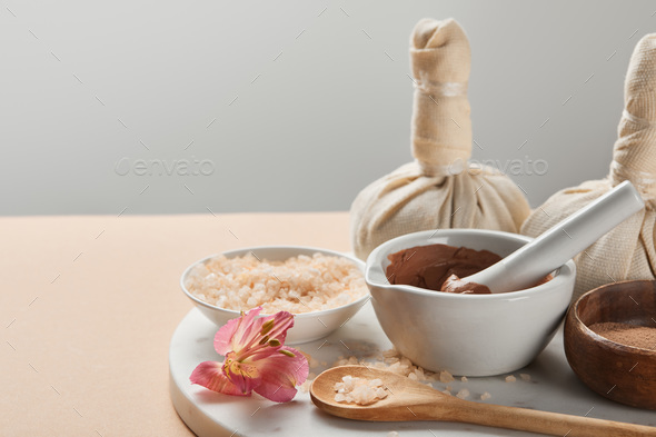 See salt wih with dried flower petals in wooden scoop on pink marble table, Stock image