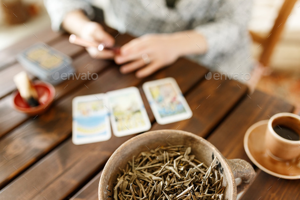 Fortune teller with tarot cards on table near burning candle.Tarot cards spread on table