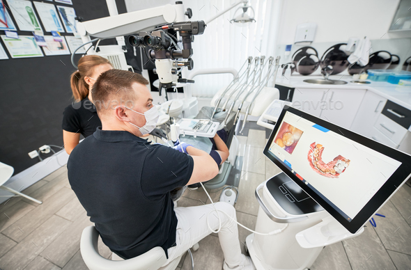 Dentist scanning patient's teeth with modern machine for intraoral ...