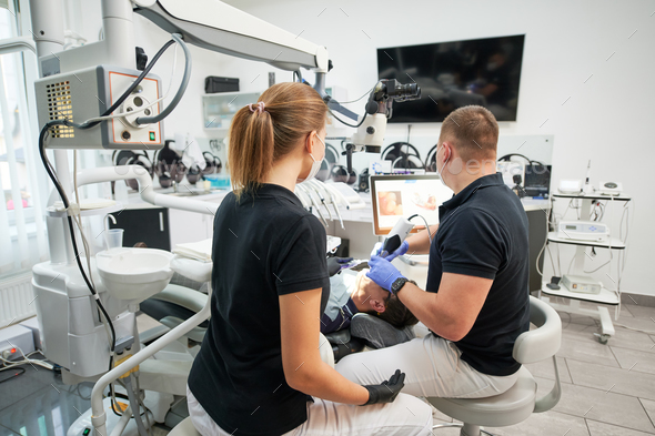 Dentist scanning patient's teeth with modern machine for intraoral ...