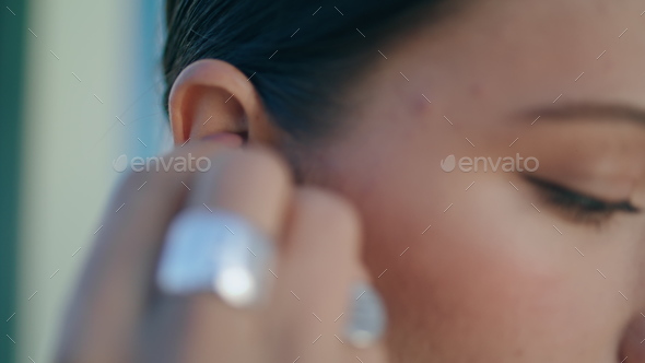 Closeup woman putting wireless earphone into ear. Girl wearing headset for music