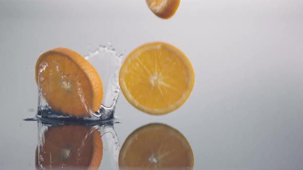 Fresh orange slices in circle shape fall down in slow motion