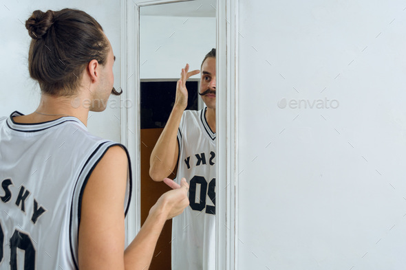 gender non-binary young person standing in the mirror to make up