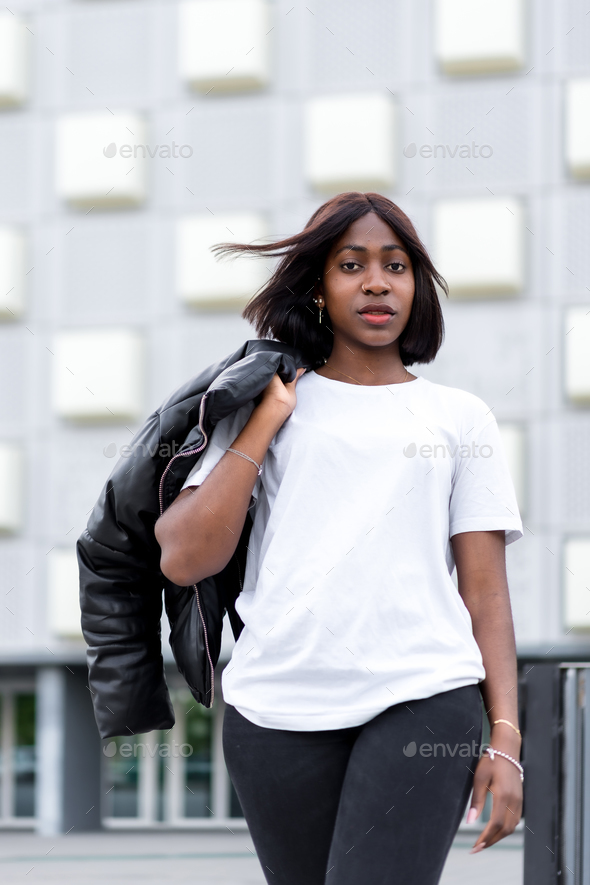 Fashionable city vibes: A young black woman strikes a pose in a stylish white tee and black pants