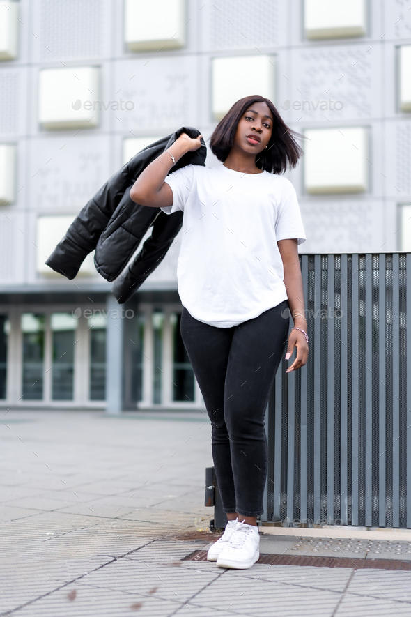 Sleek and chic: A young black woman poses in a fashionable white t-shirt  and black pants Stock Photo by Unai82