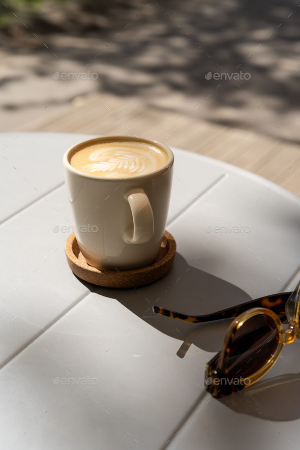 Cup with cappuccino and sunglasses on cafe terrace. Travel, vacation concept. - Stock Photo - Images