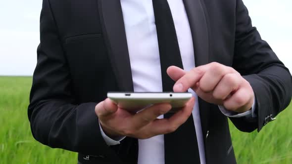 Businessman in Suit with Tablet in the Field alt