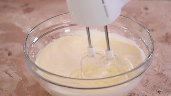 The girl chef add egg yolks to the whipped egg whites and mix together.