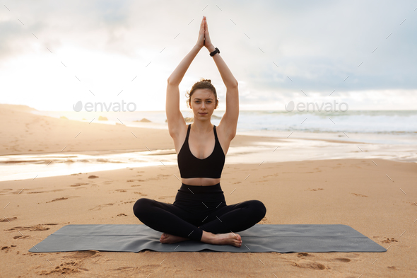 Calm slim woman practicing yoga and meditating, enjoying training on beach  near sea, exercising Stock Photo by Prostock-studio