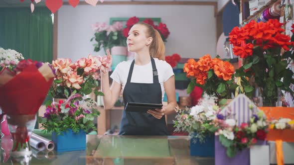 Botany and Working with Plants Florist Woman Takes Inventory in a Flower Shop a Female Uses a Screen alt