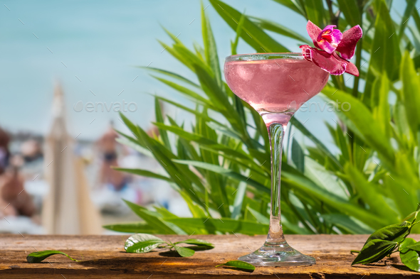 Summer drinks. Pink daiquiri alcoholic cocktail decorated flower on beach bar. Sea resort.