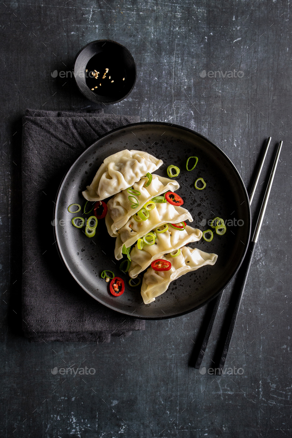 A plate with fresh gyoza dumpling on black plate and background with chopsticks - Stock Photo - Images