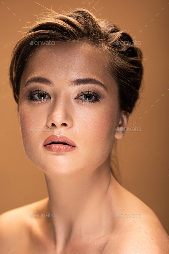 young beautiful nude woman with shiny makeup isolated on beige Stock