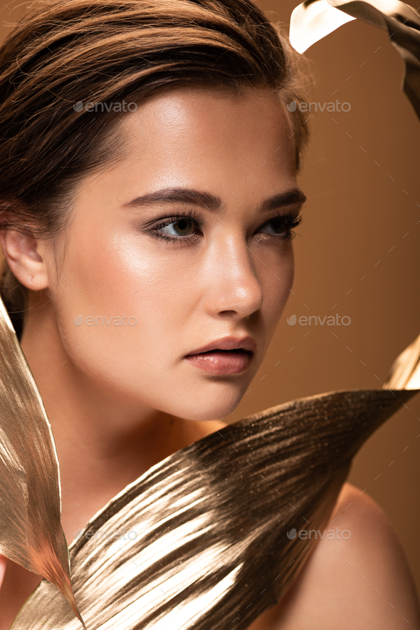 beautiful young naked woman with decorative golden leaves isolated on